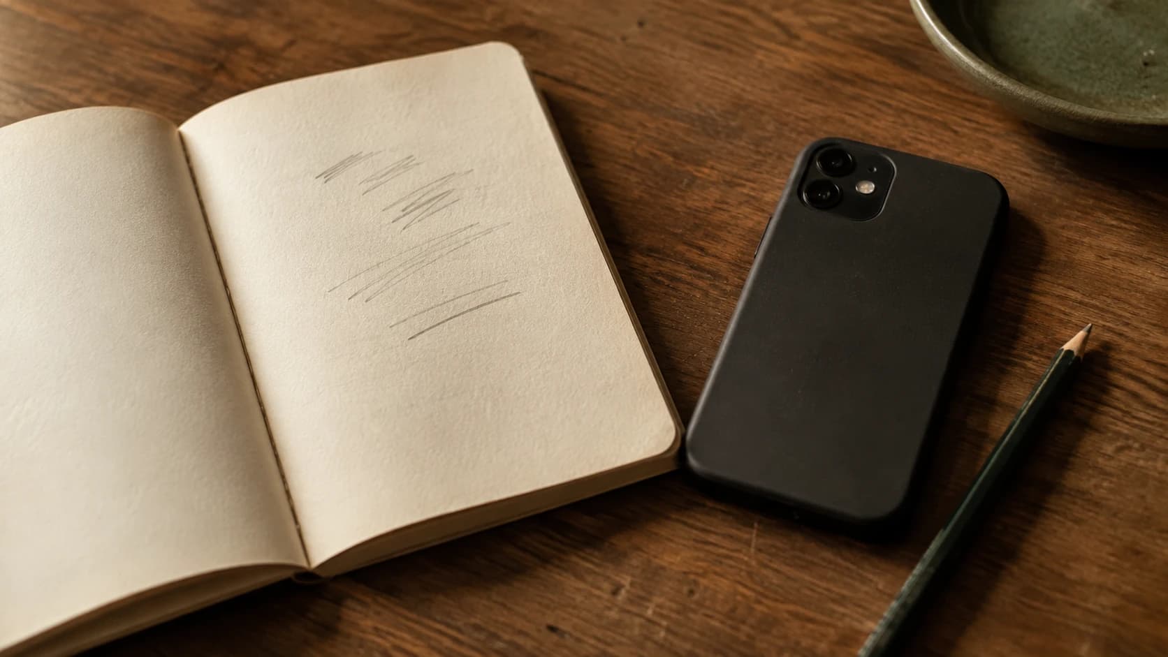 Un téléphone et un petit carnet de papier côte à côte sur une table, tous deux servant à prendre des notes