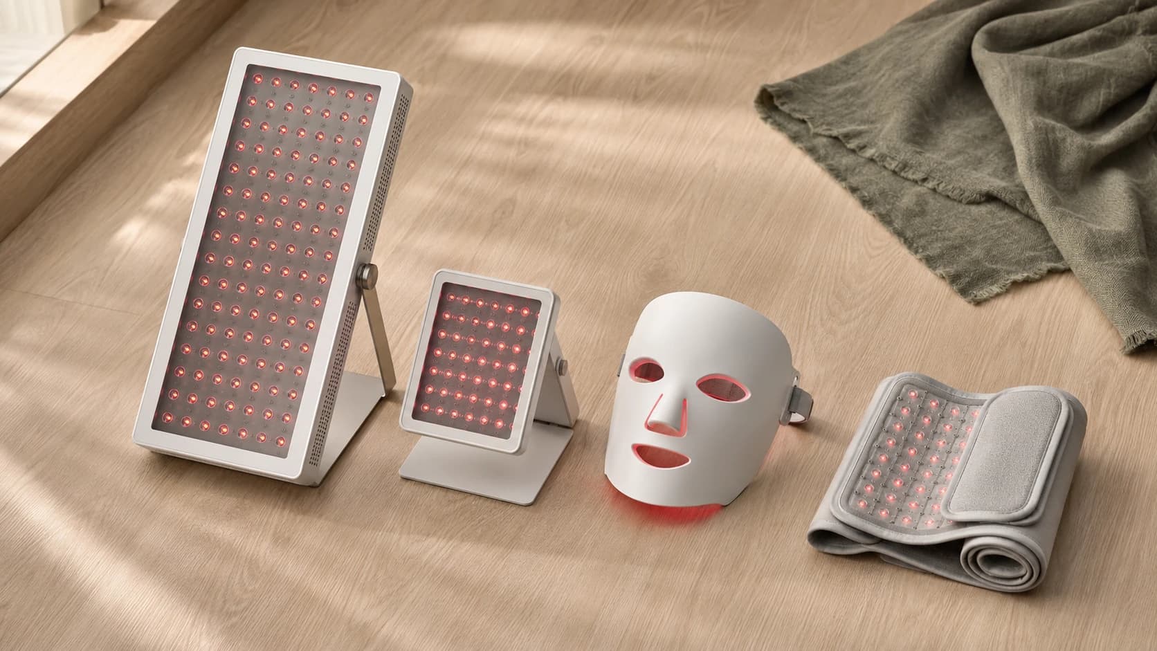 Four unbranded red light therapy devices side by side: a large panel, a small panel, a face mask and a flexible wrap