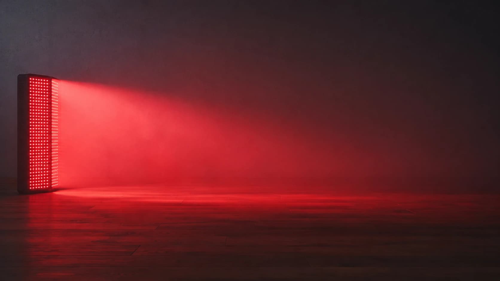 A red light therapy panel with its light growing dimmer and wider across the floor as distance increases