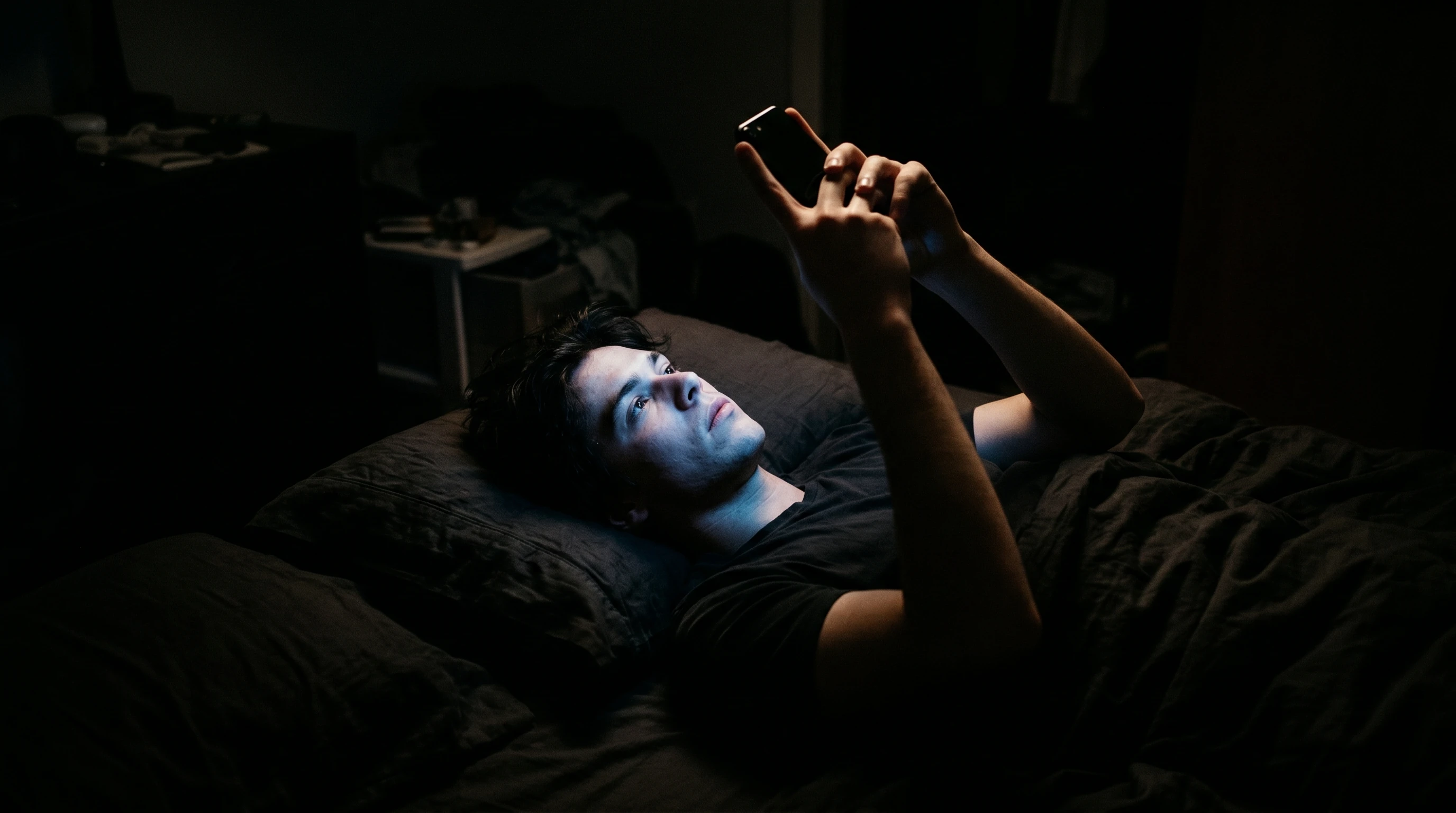 Smartphone screen emitting blue light in a dark bedroom disrupting sleep