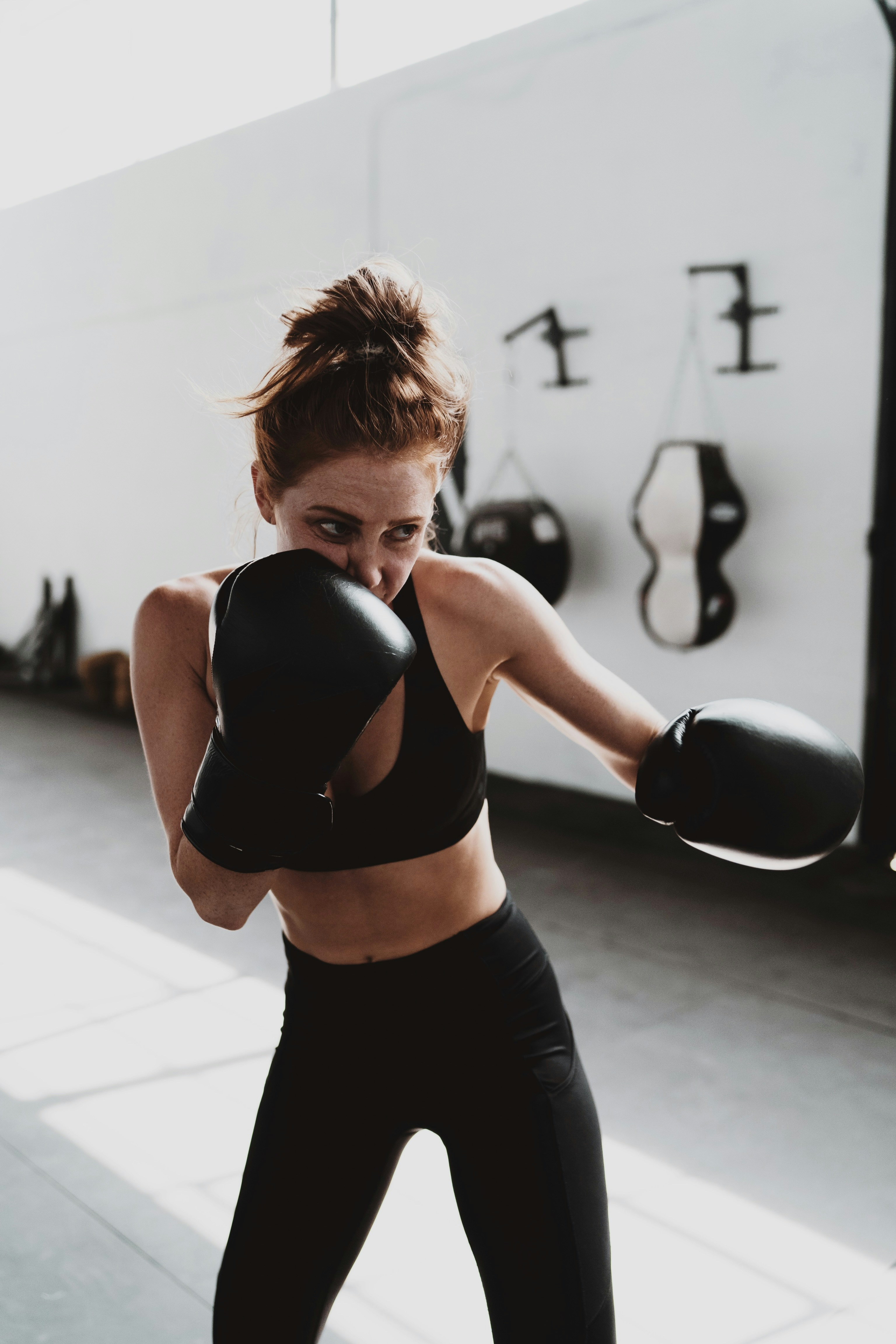 A fit woman performing a dumbbell shoulder press in a gym, wearing activewear, with a focused expression, symbolizing strength training for natural metabolism boosting.